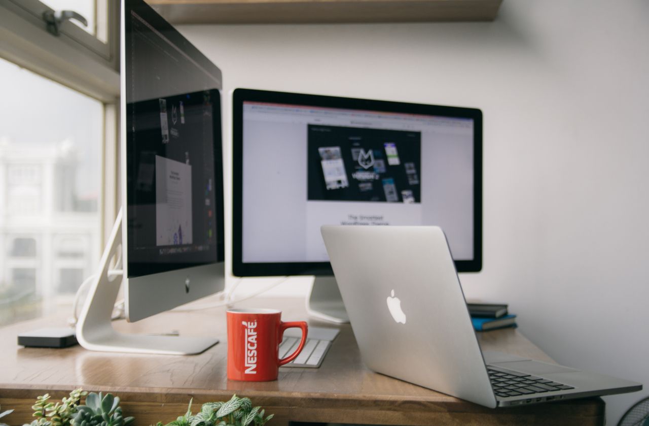 team-02 A bright modern office setup with computers and a mug on a desk.